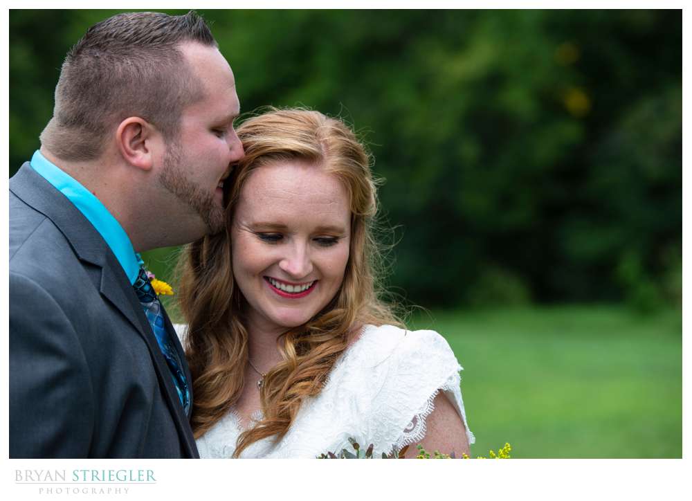 bride and groom kissing in field